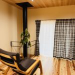 暖炉のある土間に取り付けたTOSOロールスクリーンTR6040キャメル。外の景色が見える開放的な空間