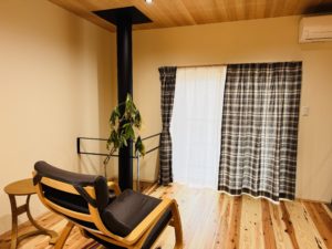 暖炉のある土間に取り付けたTOSOロールスクリーンTR6040キャメル。外の景色が見える開放的な空間