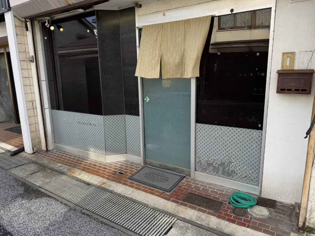 経年劣化で白く剥がれた既存のガラスフィルム。三次市の理容室、貼替前の店頭外観